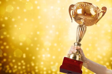 Close-up human hand holding golden Trophy on blurred  background