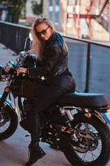 Fototapeta na wymiar Mature blond woman is sitting on her retro bike while posing for photographer.