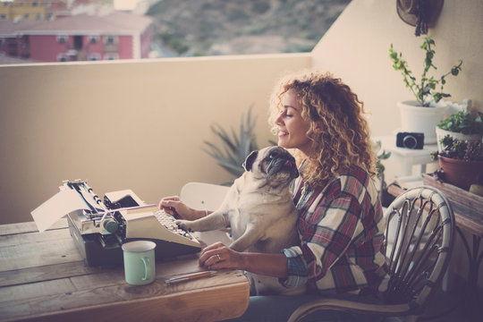 cute couple of best friends together - woman with pug sitting on her legs, old job writing with a type machine in the terrace of her house - outdoor girl with her cute dog