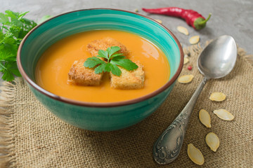 Soup of pumpkin puree and small croutons on a blue background. Close-up. Concept of the autumn menu.