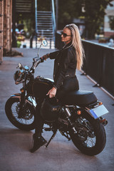 Fototapeta na wymiar Portrait of beautiful woman in sunglasses and leather clothing on the motorbike.