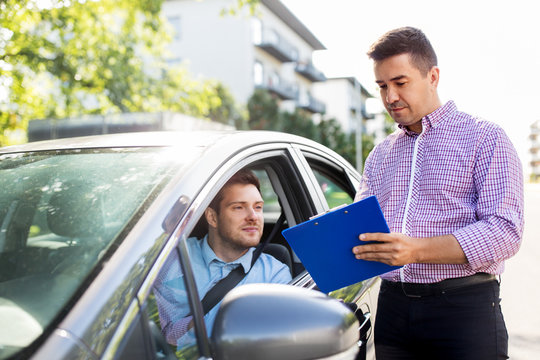 education, examination and people concept - driving school instructor with clipboard and male driver in car