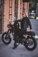 Obraz na płótnie Canvas Sexy dramatic woman is parking her shiny new motorbike next to brick wall.