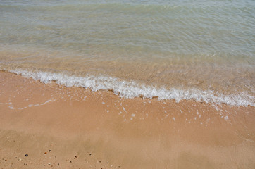 beach and beautiful tropical sea. Closeup image of beautiful sea waves breaking on shore. Wet sand and water splashes on the beach.