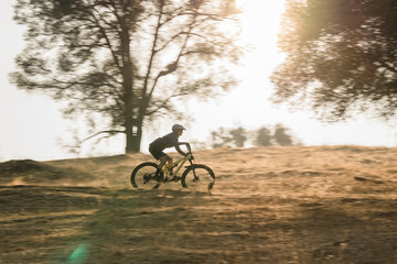 Fototapeta na wymiar female mountain bike rider riding in fall during sunset