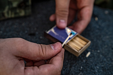 Obraz premium The man holds a burning match in his hand. In the other hand a box of matches