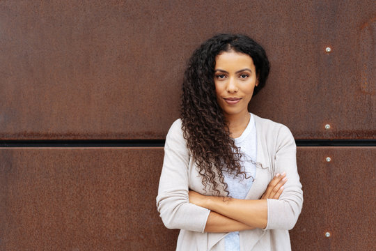 Confident young woman posing against a wall