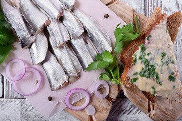Salted sprats carcass served on piece of parchment with parsley and red onion