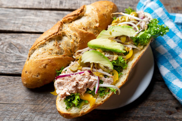 Tuna sub sandwich in rustic baguette with avocado, olives and sprouts