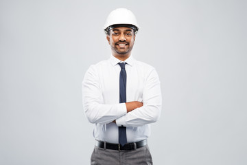 architecture, construction business and people concept - smiling indian male architect in helmet over grey background