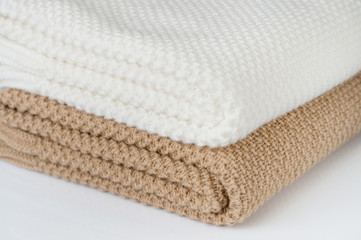 White and bronze plaids are stacked on a white surface. Close up. 