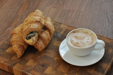 cup of coffee and croissants on wooden table