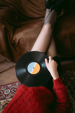 Woman listening vinyl at home. Retro woman holding a vinyl in her hand
