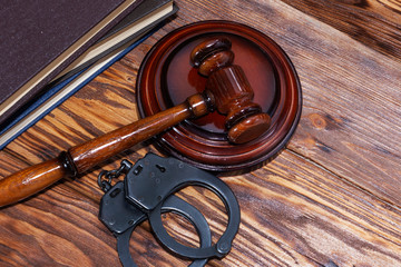 Handcuffs and a wooden gavel in front of manila folders.