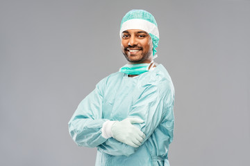 medicine, surgery and people concept - smiling indian male doctor or surgeon in protective wear...