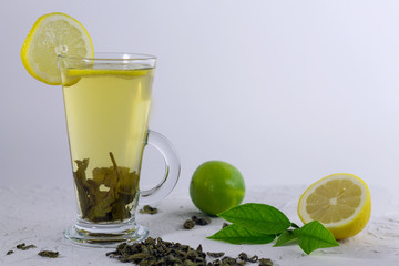 glass of green tea with yellow lemon and lime on white table