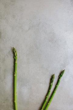 Three fresh cut asparagus spears on gray rustic background