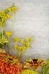 Vertical flat lay (background) of orange and yellow flowers on weathered, white-painted wood, with copy space