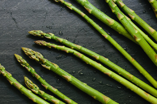 Fresh picked asparagus spears on black slate countertop