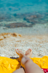 woman legs on yellow blanket at sunny beach close up