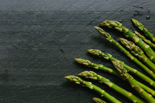 Close up of fresh picked asparagus tips on black slate countertop