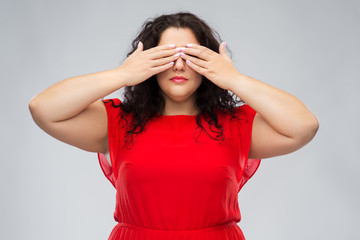 people and vision concept - woman in red dress closing her eyes by hands over grey background