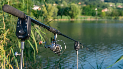  Closeup of a reel fishing rod on a prop and water background.