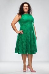 Naklejka premium people and portrait concept - happy woman in green dress posing over grey background