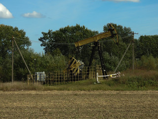 Oil pump wells for underground oil production works in the field on an autumn day