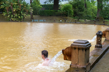 Adult man in mineral thermal pool in the Terra Nostra park at Furnas, Sao Miguel island, Azores,...