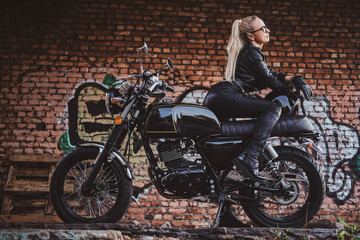 Plakat Portrait of mature attractive lady next to her vintage motorbike and graffiti brick wall.