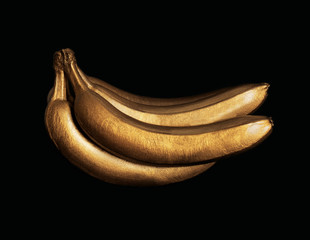 Bunch of gold painted bananas on black background