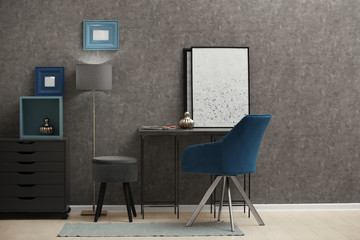 Stylish room interior with modern furniture and comfortable chair near grey wall
