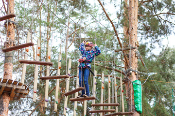 Girl having fun in an adventure park. kid climbing a rope playground. kid climbing a rope playground.