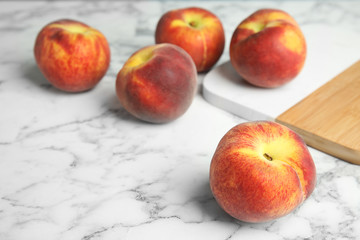 Fresh peaches and wooden board on marble table, space for text