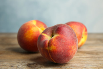 Fresh juicy peaches on wooden table against blue background