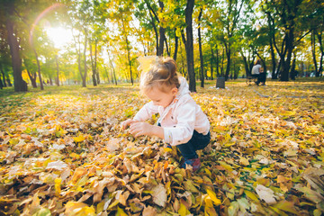 little smiling blond cute toddler girl at autumn city park