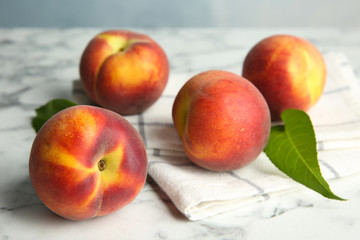 Fresh juicy peaches, leaves and fabric on marble table