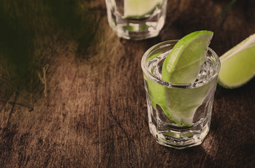 Cachaca - Brazilian strong alcoholic beverage from cane sugar, lime vodka, vintage wooden background, selective focus