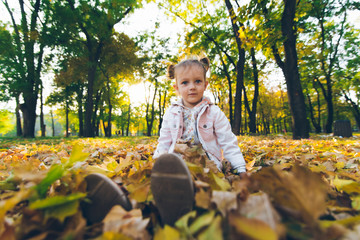 little smiling blond cute toddler girl at autumn city park