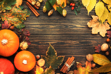 Naklejka na ściany i meble Autumn food top view, Thanksgiving or Halloween background: pumpkins, nuts, fallen leaves and spices on brown wooden background. Seasonal fall background for Thanksgiving dinner 