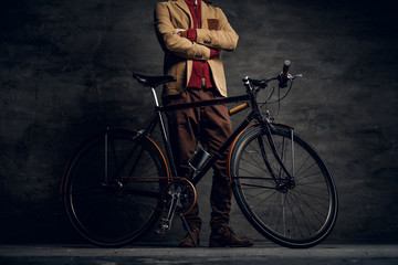 Man with his bicycle is posing for photographer at dark photo studio.