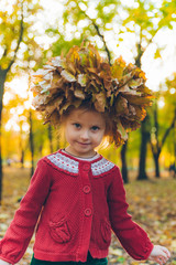 little toddler girl playing with maple leaves wreath