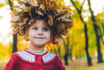 little toddler girl playing with maple leaves wreath