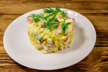 Salad with crab sticks, sweet corn, cucumber, eggs and mayonnaise on wooden table