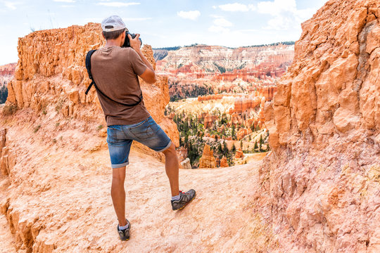 Man tourist person standing taking picture of view with camera at Queens Garden Navajo Loop trail at Bryce Canyon National Park in Utah