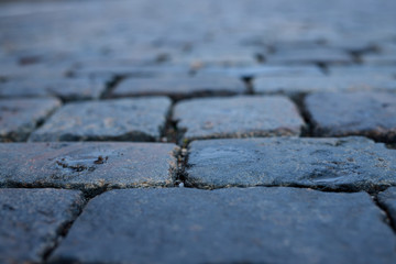 Obraz premium Stone pavement in perspective. Old street paved with stone blocks. Shallow depth of field. Vintage grunge texture.