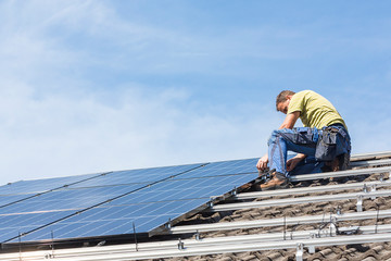 Installing solar photovoltaic panel system. Solar panel technician installing solar panels on roof. Alternative energy ecological concept.