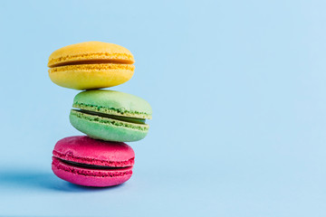 Colorful macaroons on a blue background, close-up, Flatley with copy space