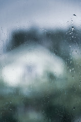 wet glass of window with raindrops, estate garden